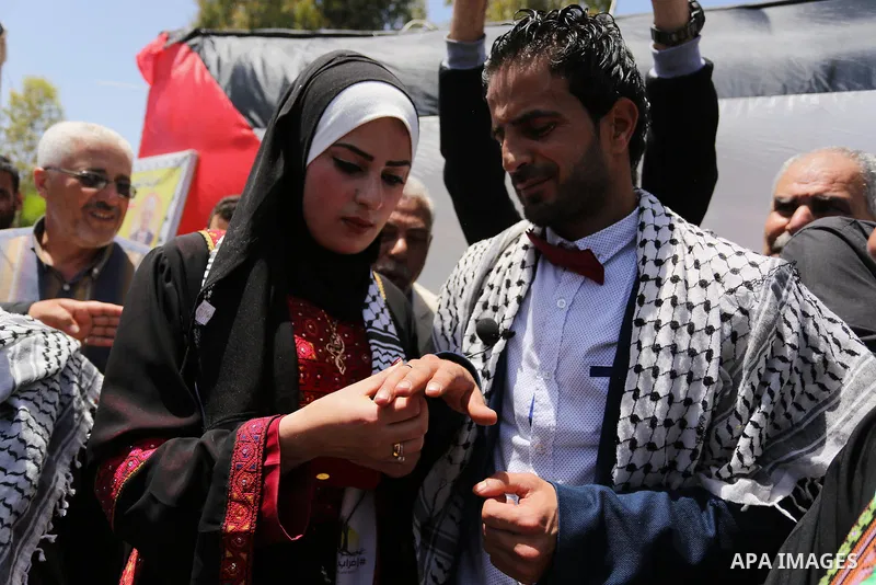 A Palestinian groom and his bride take part in their marriage ceremony at a sit-in in support of Palestinian hunger-striking prisoners held in Israeli jails, on May 8, 2017, in Gaza City. Photo by Ashraf Amra