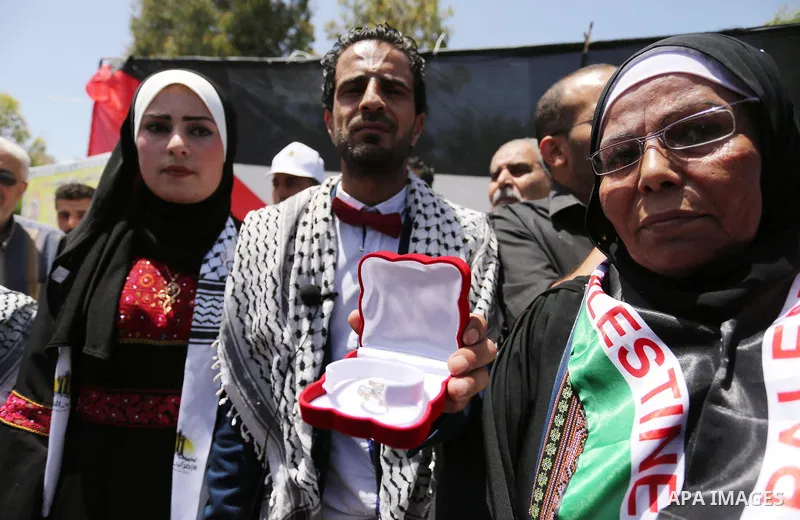 A Palestinian groom and his bride take part in their marriage ceremony at a sit-in in support of Palestinian hunger-striking prisoners held in Israeli jails, on May 8, 2017, in Gaza City. Photo by Ashraf Amra