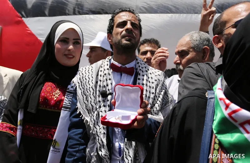 A Palestinian groom and his bride take part in their marriage ceremony at a sit-in in support of Palestinian hunger-striking prisoners held in Israeli jails, on May 8, 2017, in Gaza City. Photo by Ashraf Amra