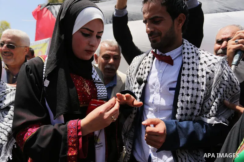 A Palestinian groom and his bride take part in their marriage ceremony at a sit-in in support of Palestinian hunger-striking prisoners held in Israeli jails, on May 8, 2017, in Gaza City. Photo by Ashraf Amra