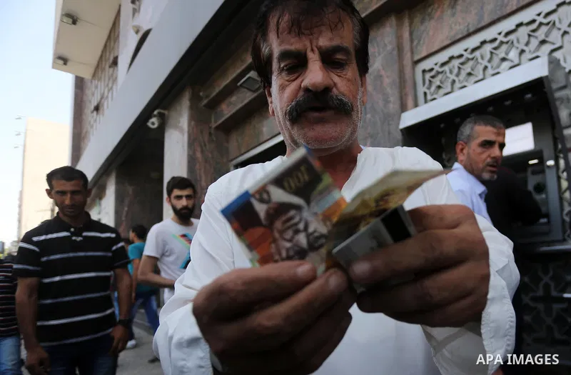 Palestinians, employed by the Palestinian Authority wait to receive their salaries from an ATM, outside a Bank in Gaza City on May 10, 2017. The salaries of Palestinian employees in Gaza strip have been reduced by about...