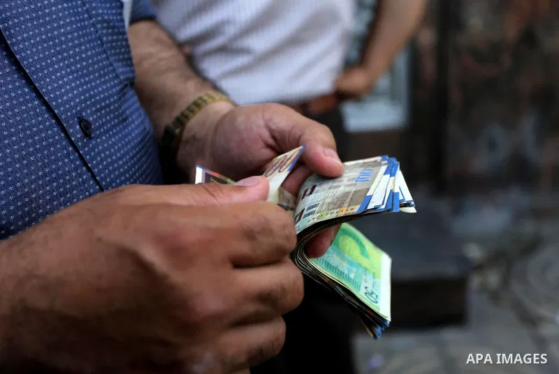 Palestinians, employed by the Palestinian Authority wait to receive their salaries from an ATM, outside a Bank in Gaza City on May 10, 2017. The salaries of Palestinian employees in Gaza strip have been reduced by about...