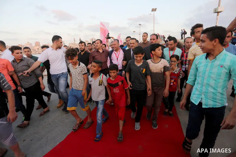 Palestinians walk on a red carpet during the 3rd Annual Red Carpet Festival for Human Rights Films at the Gaza seaport, on May 12, 2017. The Red Carpet Festival is held in the Gaza Strip this year for the third year in a...