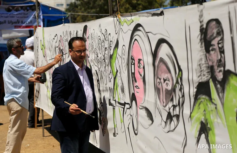 Palestinian artists paint a mural in solidarity with Palestinian prisoners on hunger strike in Israeli jails, and to commemorate the 68th anniversary of the "Nakba" or "catastrophe" in Arabic in reference to the establis...