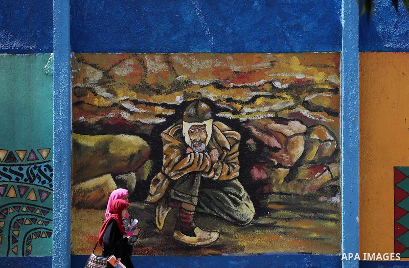 Palestinian women walk past a mural on the occasion of the 69th anniversary of the "Nakba" or "catastrophe" in Arabic in reference to the establishment in 1948 of the state of Israel, in Gaza city on May 15, 2017. Nakba"...