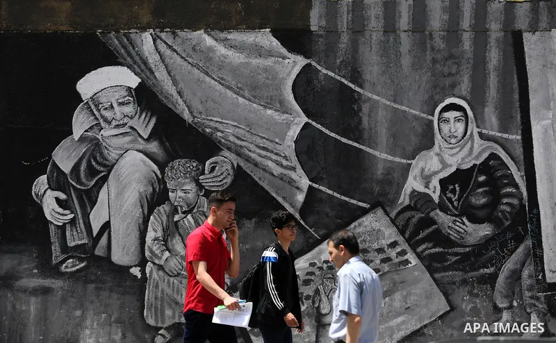 Palestinians walk past a mural on the occasion of the 69th anniversary of the "Nakba" or "catastrophe" in Arabic in reference to the establishment in 1948 of the state of Israel, in Gaza city on May 15, 2017. Nakba" mean...
