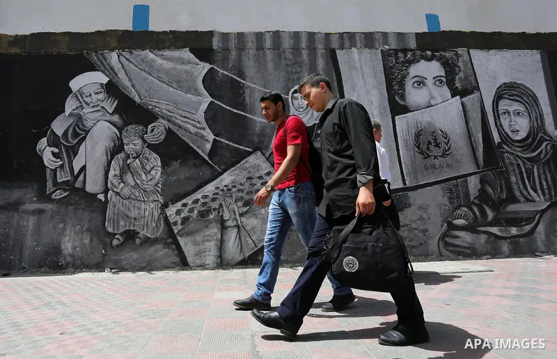 Palestinians walk past a mural on the occasion of the 69th anniversary of the "Nakba" or "catastrophe" in Arabic in reference to the establishment in 1948 of the state of Israel, in Gaza city on May 15, 2017. Nakba" mean...