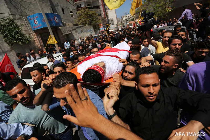 Palestinian mourners carry the body of Mohammed Majed Bakr, a 25-year-old fisherman who died from his injuries after an Israeli patrol vessel fired at a fishing boat, during his funeral in Gaza City on May 16, 2017. The...