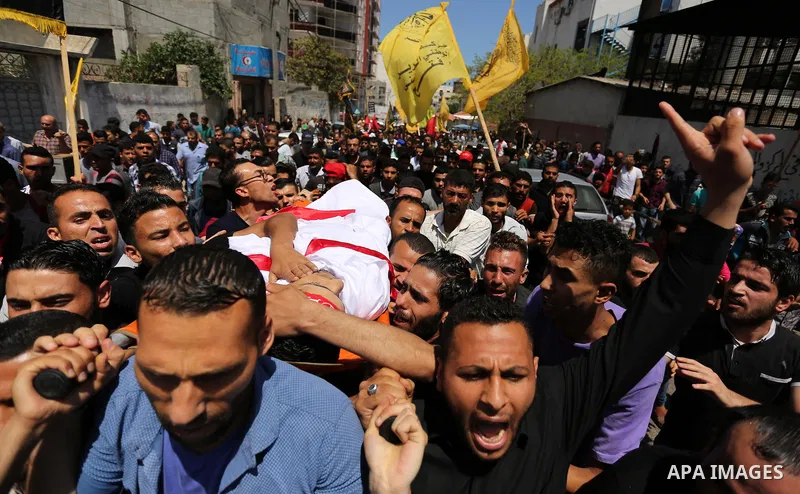 Palestinian mourners carry the body of Mohammed Majed Bakr, a 25-year-old fisherman who died from his injuries after an Israeli patrol vessel fired at a fishing boat, during his funeral in Gaza City on May 16, 2017. The...