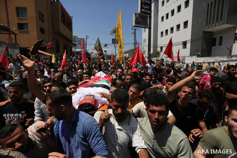 Palestinian mourners carry the body of Mohammed Majed Bakr, a 25-year-old fisherman who died from his injuries after an Israeli patrol vessel fired at a fishing boat, during his funeral in Gaza City on May 16, 2017. The...