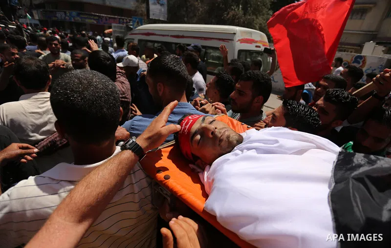 Palestinian mourners carry the body of Mohammed Majed Bakr, a 25-year-old fisherman who died from his injuries after an Israeli patrol vessel fired at a fishing boat, during his funeral in Gaza City on May 16, 2017. The...