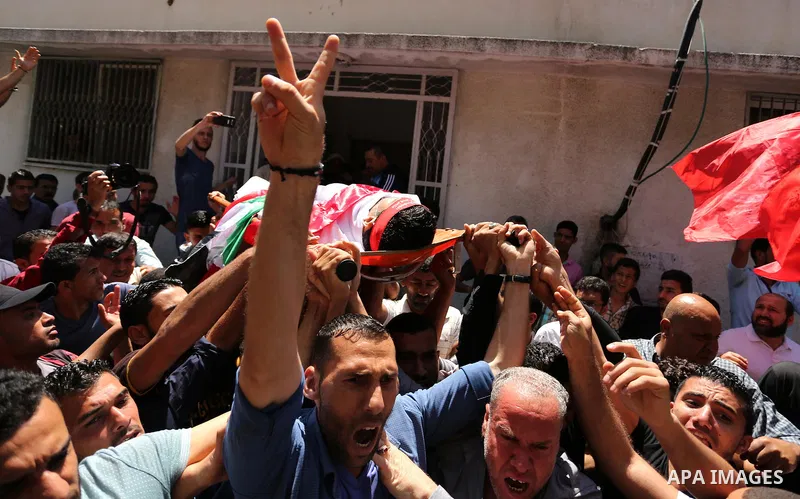Palestinian mourners carry the body of Mohammed Majed Bakr, a 25-year-old fisherman who died from his injuries after an Israeli patrol vessel fired at a fishing boat, during his funeral in Gaza City on May 16, 2017. The...