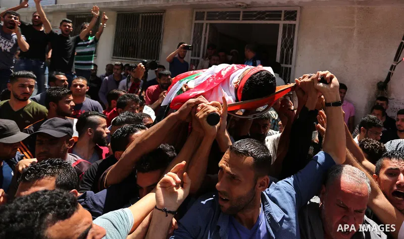 Palestinian mourners carry the body of Mohammed Majed Bakr, a 25-year-old fisherman who died from his injuries after an Israeli patrol vessel fired at a fishing boat, during his funeral in Gaza City on May 16, 2017. The...