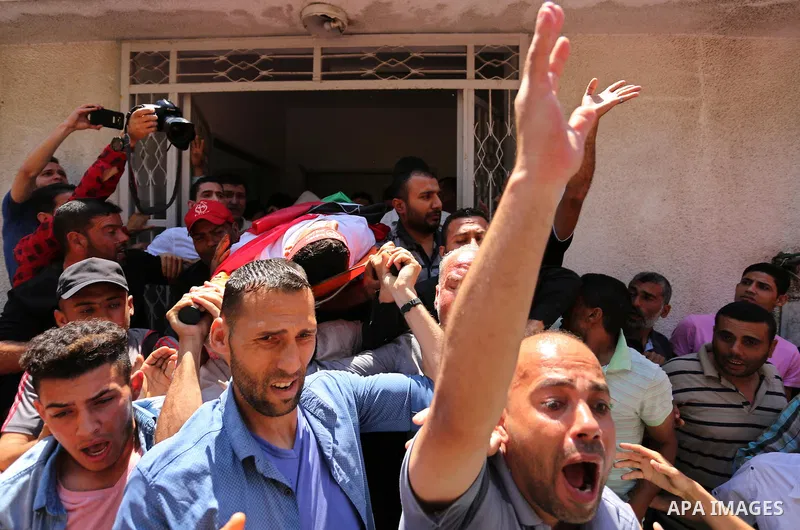 Palestinian mourners carry the body of Mohammed Majed Bakr, a 25-year-old fisherman who died from his injuries after an Israeli patrol vessel fired at a fishing boat, during his funeral in Gaza City on May 16, 2017. The...