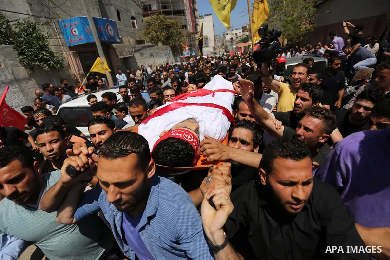 Palestinian mourners carry the body of Mohammed Majed Bakr, a 25-year-old fisherman who died from his injuries after an Israeli patrol vessel fired at a fishing boat, during his funeral in Gaza City on May 16, 2017. The...