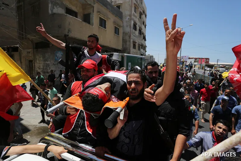 Palestinian mourners carry the body of Mohammed Majed Bakr, a 25-year-old fisherman who died from his injuries after an Israeli patrol vessel fired at a fishing boat, during his funeral in Gaza City on May 16, 2017. The...