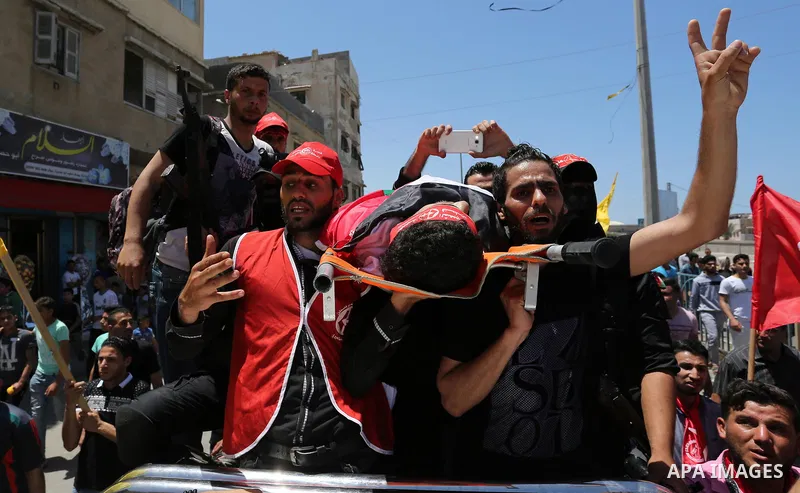 Palestinian mourners carry the body of Mohammed Majed Bakr, a 25-year-old fisherman who died from his injuries after an Israeli patrol vessel fired at a fishing boat, during his funeral in Gaza City on May 16, 2017. The...