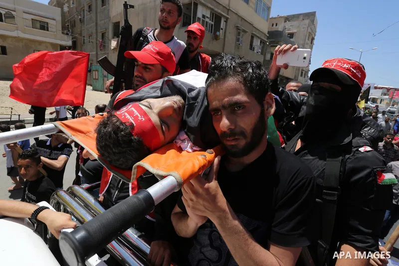 Palestinian mourners carry the body of Mohammed Majed Bakr, a 25-year-old fisherman who died from his injuries after an Israeli patrol vessel fired at a fishing boat, during his funeral in Gaza City on May 16, 2017. The...