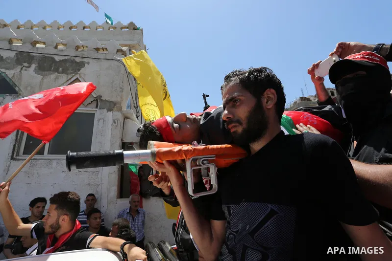 Palestinian mourners carry the body of Mohammed Majed Bakr, a 25-year-old fisherman who died from his injuries after an Israeli patrol vessel fired at a fishing boat, during his funeral in Gaza City on May 16, 2017. The...