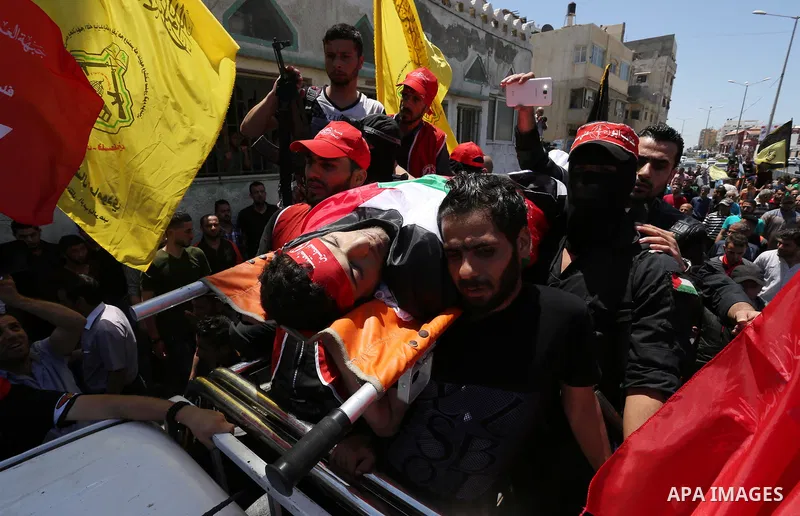 Palestinian mourners carry the body of Mohammed Majed Bakr, a 25-year-old fisherman who died from his injuries after an Israeli patrol vessel fired at a fishing boat, during his funeral in Gaza City on May 16, 2017. The...