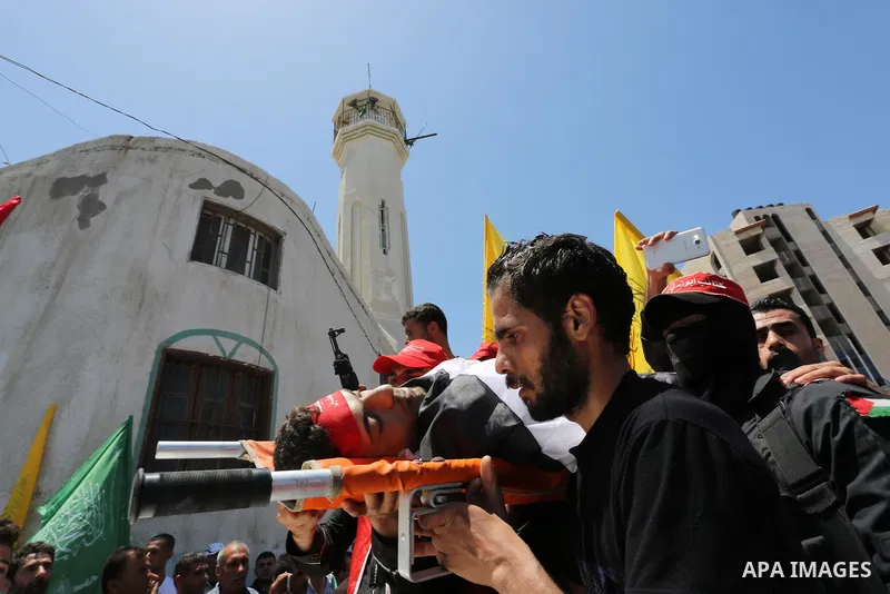 Palestinian mourners carry the body of Mohammed Majed Bakr, a 25-year-old fisherman who died from his injuries after an Israeli patrol vessel fired at a fishing boat, during his funeral in Gaza City on May 16, 2017. The...