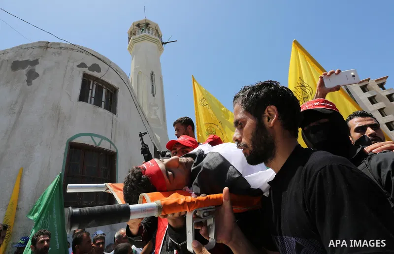 Palestinian mourners carry the body of Mohammed Majed Bakr, a 25-year-old fisherman who died from his injuries after an Israeli patrol vessel fired at a fishing boat, during his funeral in Gaza City on May 16, 2017. The...