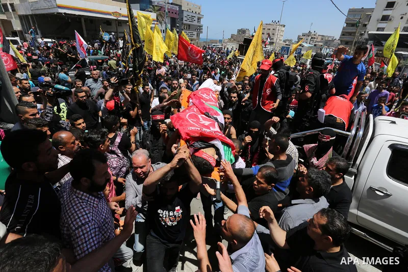 Palestinian mourners carry the body of Mohammed Majed Bakr, a 25-year-old fisherman who died from his injuries after an Israeli patrol vessel fired at a fishing boat, during his funeral in Gaza City on May 16, 2017. The...