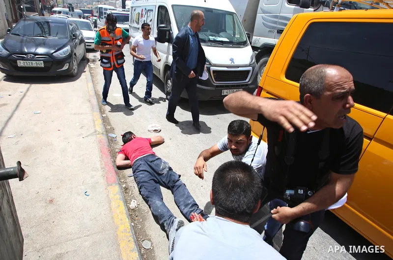 Palestinians carry a wounded photojournalist after he was allegedly killed by Israeli settler during clashes at Huwwara village, near the West Bank, 18 May 2017. According to media sources, a Palestinian was allegedly sh...