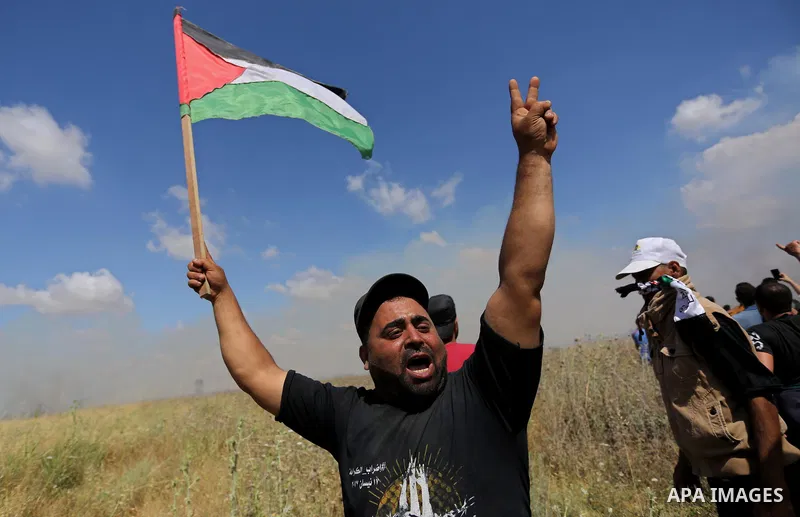 A Palestinian protester waves a national flag during clashes with Israeli security forces following a protest against the blockade on Gaza Strip, near Nahal Oz crossing east of Gaza City on May 19, 2017. Photo by Ashraf...