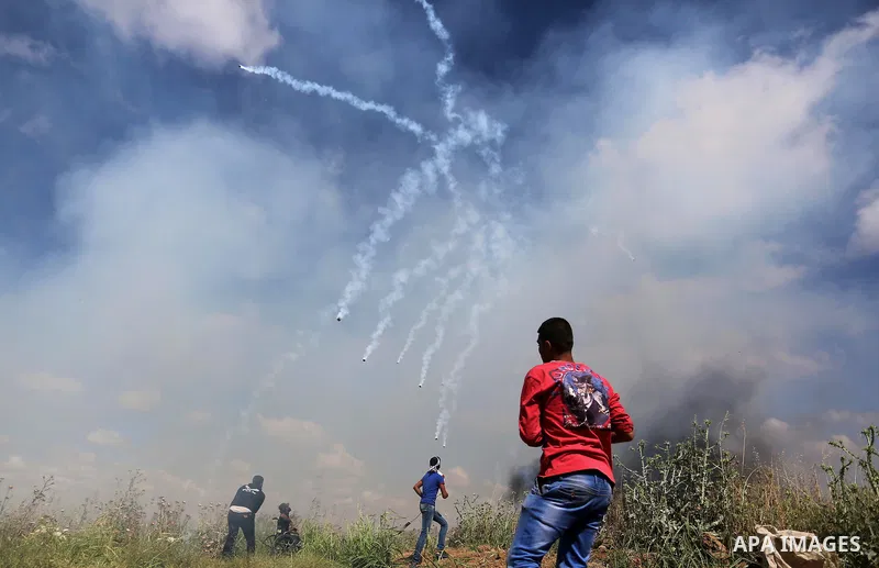 Palestinians protesters run for cover from tear gas fired by Israeli security forces during clashes following a protest against the blockade on Gaza Strip, near Nahal Oz crossing east of Gaza City on May 19, 2017. Photo...