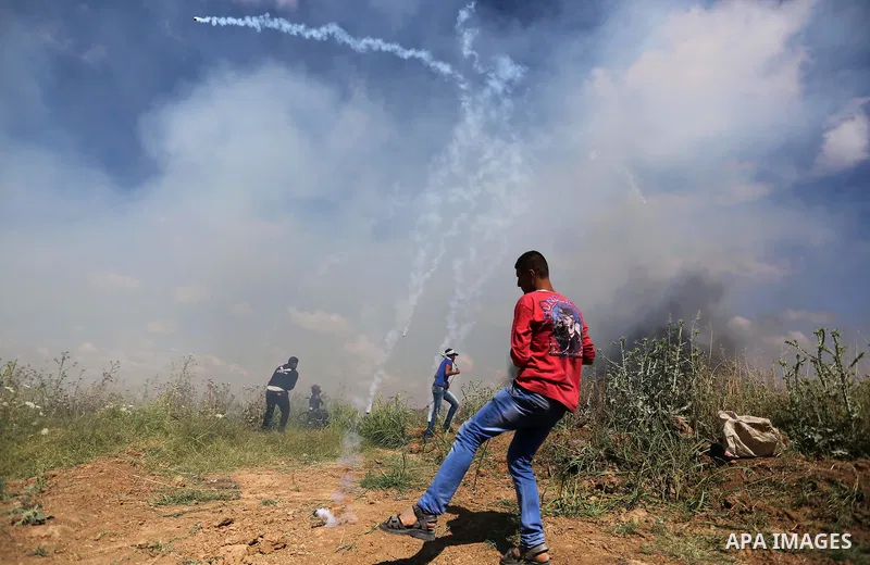 A Palestinian protester kicks back a tear gas fired by Israeli security forces during clashes following a protest against the blockade on Gaza Strip, near Nahal Oz crossing east of Gaza City on May 19, 2017. Photo by Ash...