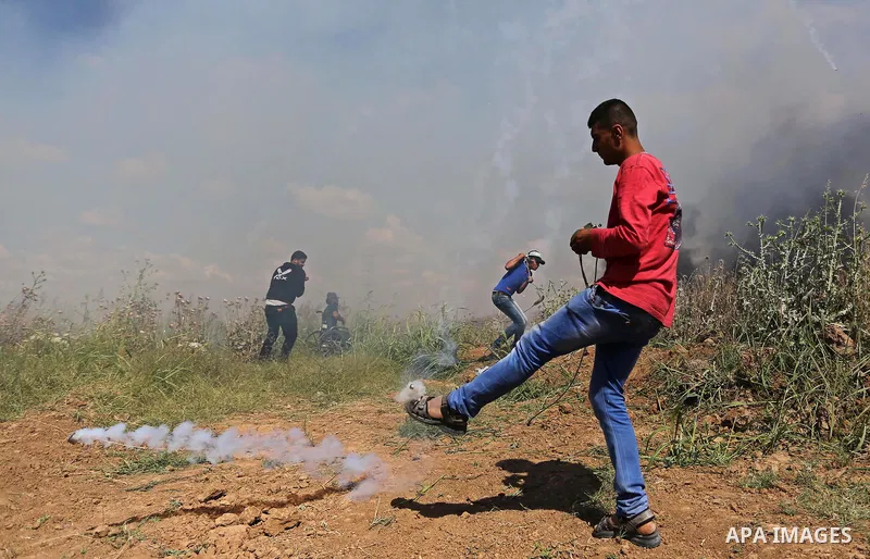 A Palestinian protester kicks back a tear gas fired by Israeli security forces during clashes following a protest against the blockade on Gaza Strip, near Nahal Oz crossing east of Gaza City on May 19, 2017. Photo by Ash...