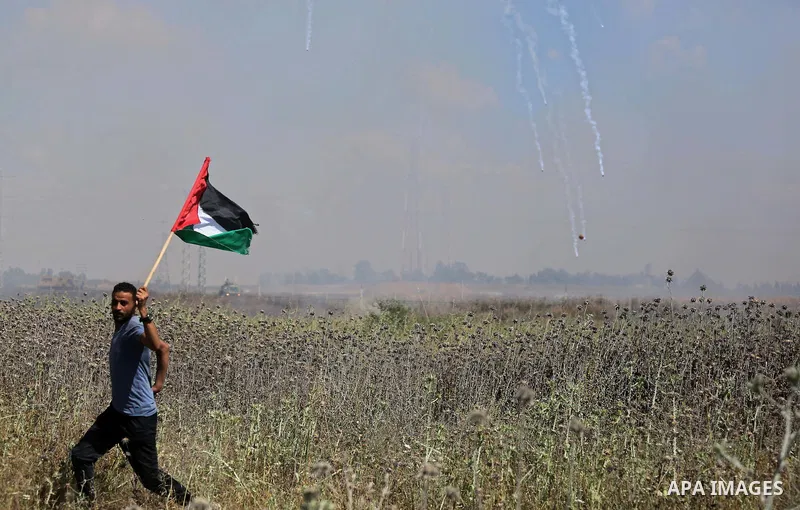 A Palestinian protester waves a national flag during clashes with Israeli security forces following a protest against the blockade on Gaza Strip, near Nahal Oz crossing east of Gaza City on May 19, 2017. Photo by Ashraf...