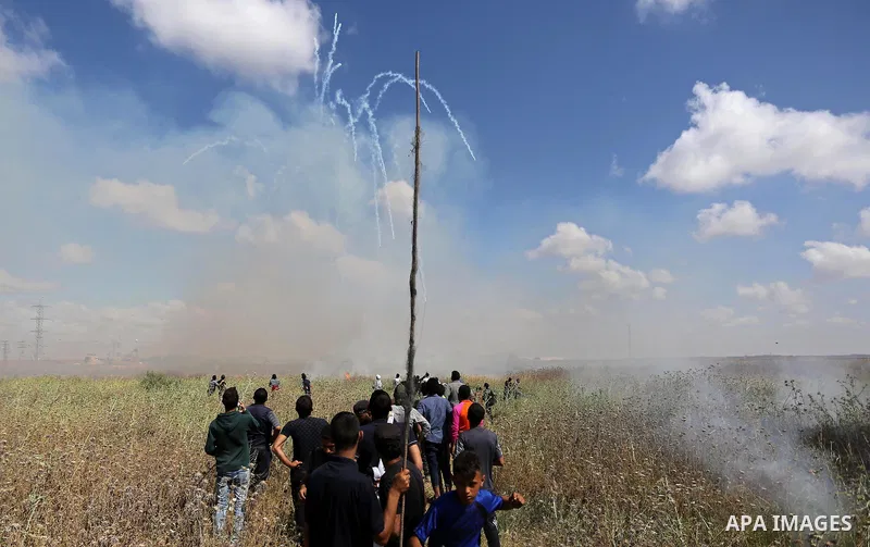 Palestinians protesters take cover from tear gas fired by Israeli security forces during clashes following a protest against the blockade on Gaza Strip, near Nahal Oz crossing east of Gaza City on May 19, 2017. Photo by...