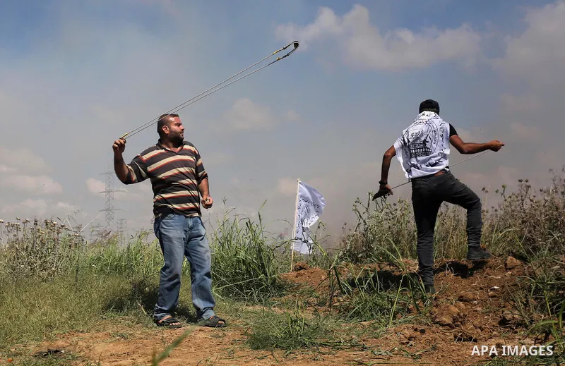 A Palestinian protester uses a slingshot to hurl stones towards Israeli security forces during clashes following a protest against the blockade on Gaza Strip, near Nahal Oz crossing east of Gaza City on May 19, 2017. Pho...