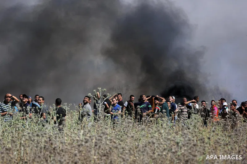 Palestinians protesters take cover from tear gas fired by Israeli security forces during clashes following a protest against the blockade on Gaza Strip, near Nahal Oz crossing east of Gaza City on May 19, 2017. Photo by...