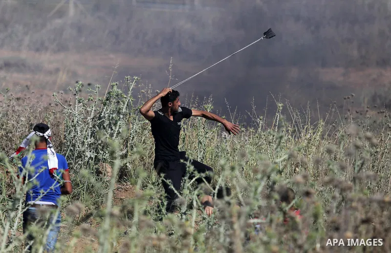 A Palestinian protester uses a slingshot to hurl stones towards Israeli security forces during clashes following a protest against the blockade on Gaza Strip, near Nahal Oz crossing east of Gaza City on May 19, 2017. Pho...
