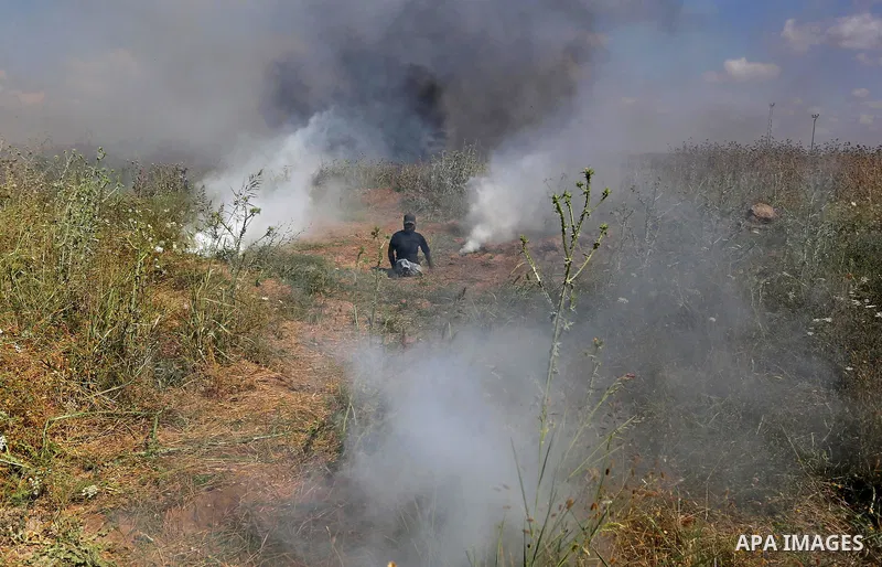 A handicapped Palestinian protester tries to run from a tear gas fired by Israeli security forces during clashes following a protest against the blockade on Gaza Strip, near Nahal Oz crossing east of Gaza City on May 19,...