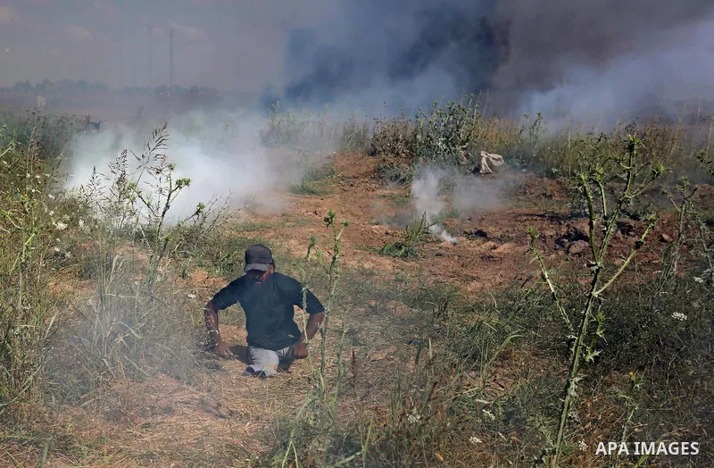 A handicapped Palestinian protester tries to run from a tear gas fired by Israeli security forces during clashes following a protest against the blockade on Gaza Strip, near Nahal Oz crossing east of Gaza City on May 19,...