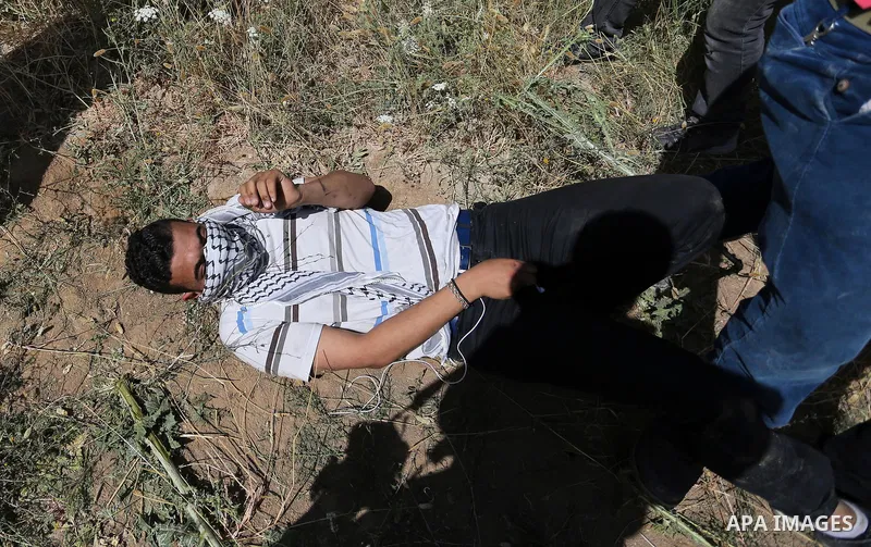 A Palestinian wounded protester lies on ground during clashes with Israeli security forces following a protest against the blockade on Gaza Strip, near Nahal Oz crossing east of Gaza City on May 19, 2017. Photo by Ashraf...