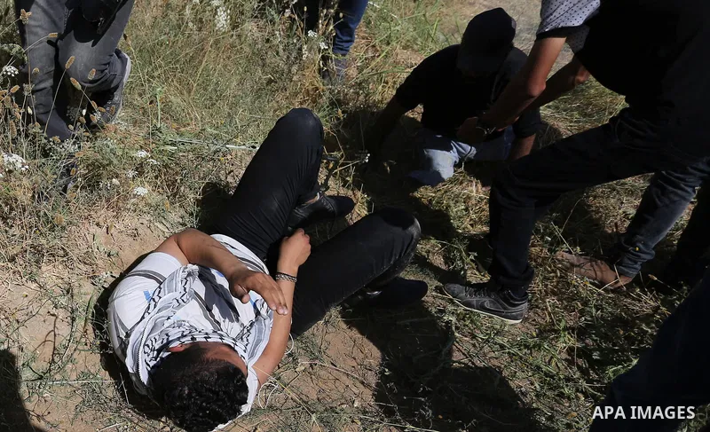 A Palestinian wounded protester lies on ground during clashes with Israeli security forces following a protest against the blockade on Gaza Strip, near Nahal Oz crossing east of Gaza City on May 19, 2017. Photo by Ashraf...