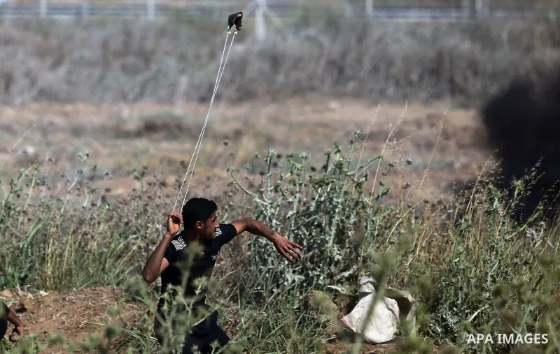 A Palestinian protester uses a slingshot to hurl stones towards Israeli security forces during clashes following a protest against the blockade on Gaza Strip, near Nahal Oz crossing east of Gaza City on May 19, 2017. Pho...