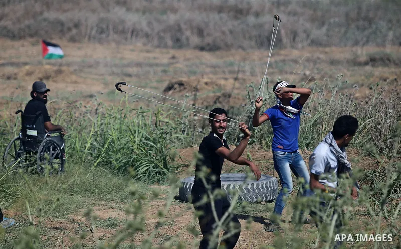 Palestinian protesters use a slingshot to hurl stones towards Israeli security forces during clashes following a protest against the blockade on Gaza Strip, near Nahal Oz crossing east of Gaza City on May 19, 2017. Photo...