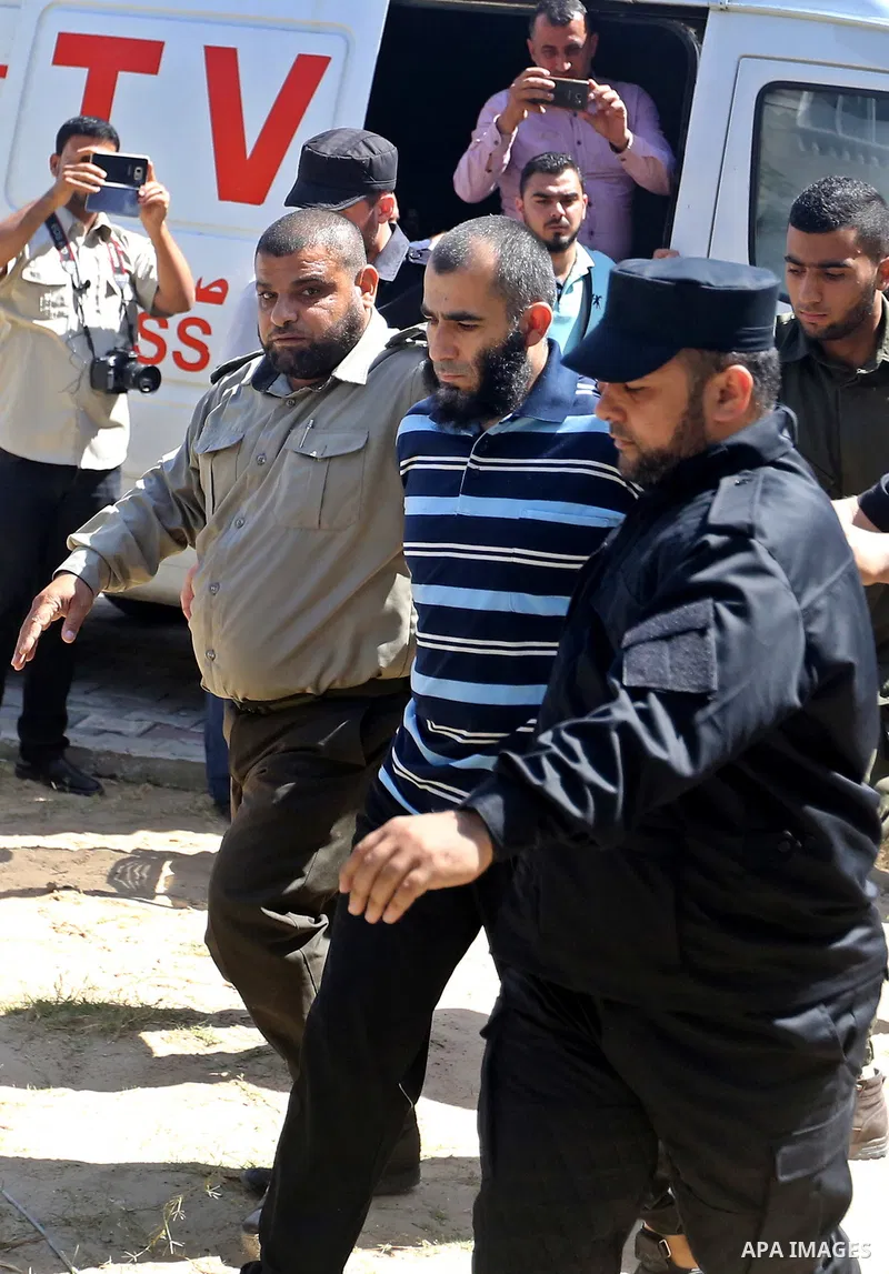 Palestinian security forces escort Ashraf Abu Leila, a 38-year-old Palestinian man convicted of the murder of Hamas military commander Mazen Faqha, out of the military court in Gaza City, on May 21, 2017. A court in the...