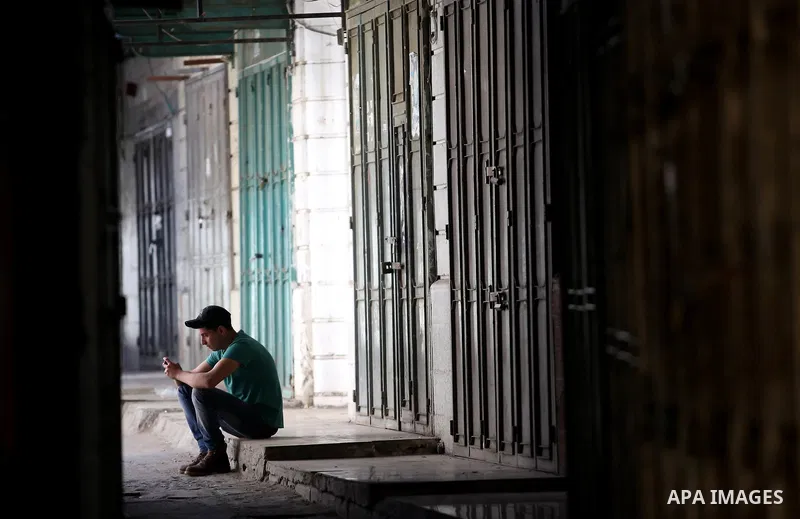A Palestinian boy sits in front of closed shops during a general strike in support of Palestinian prisoners on hunger strike in Israeli jails, in the market in the Old City of the West Bank town of Nablus, on May 22, 201...