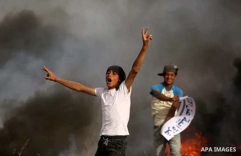 A Palestinian protester flashses the victory sign during clashes with Israeli security forces following a protest against the blockade on Gaza Strip, near the border fence east of Gaza City on May 22, 2017. Photo by Ashr...