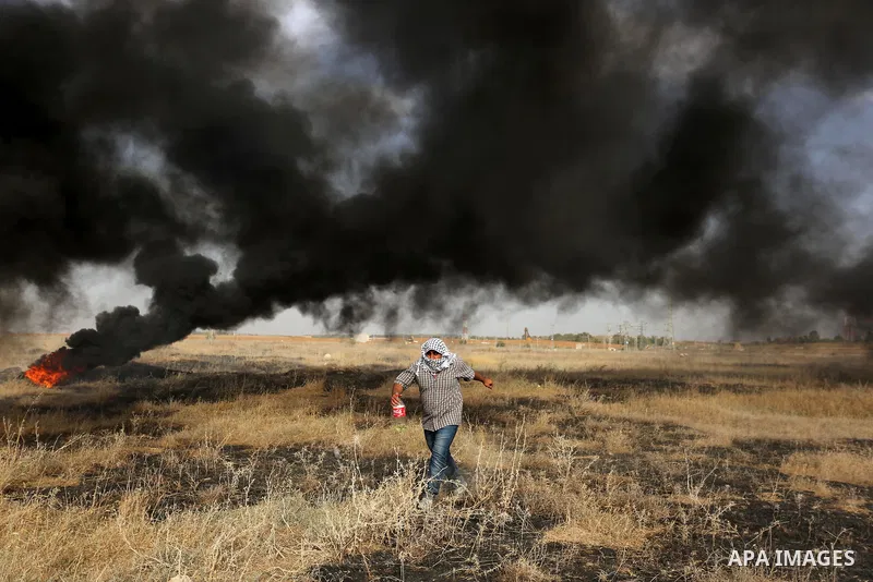 A Palestinian protester burns tires during clashes with Israeli security forces following a protest against the blockade on Gaza Strip, near the border fence east of Gaza City on May 22, 2017. Photo by Ashraf Amra