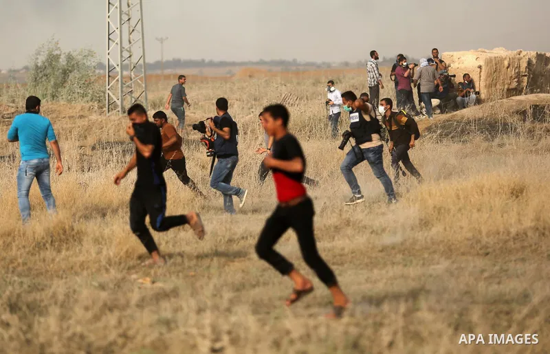 Palestinian protesters run for cover from tear gas canister fired by Israeli security forces during clashes following a protest against the blockade on Gaza Strip, near the border fence east of Gaza City on May 22, 2017....