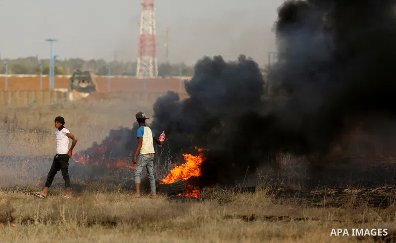 Palestinian protesters burn tires during clashes with Israeli security forces following a protest against the blockade on Gaza Strip, near the border fence east of Gaza City on May 22, 2017. Photo by Ashraf Amra