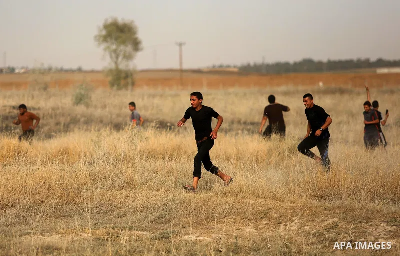 Palestinian protesters run for cover from tear gas canister fired by Israeli security forces during clashes following a protest against the blockade on Gaza Strip, near the border fence east of Gaza City on May 22, 2017....
